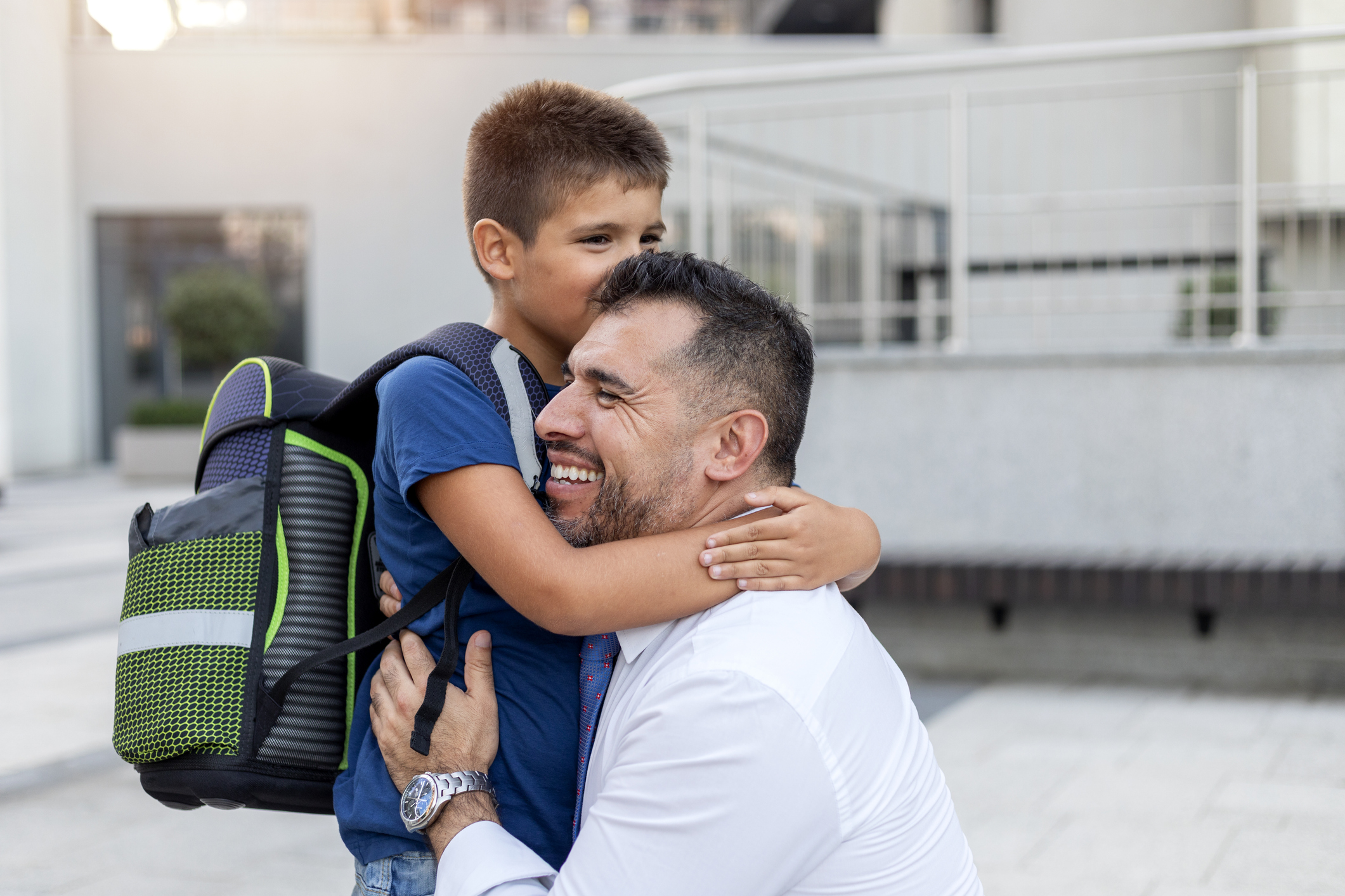 A photo of a boy saying goodbye to his father before entering the school building